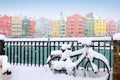 Snowy weather, colorful city houses, fence, bright teal water of Inn river and a bike covered with fresh snow in Innsbruck