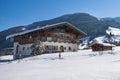 Austrian traditional tyrolean family house in the snow. Alpine home with winter snowy mountains background. Royalty Free Stock Photo