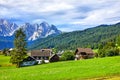 Austrian village among green meadows and Alps Royalty Free Stock Photo