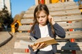Autdoor portrait of offended little girl. A girl is reading thick book, offendedly pouting her lips Royalty Free Stock Photo