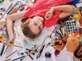 Authentic artist children girl paints on floor. Top view.