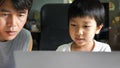 Authentic asian child boy using laptop with father. Kid smile with happy face looking to notebook for studying at home. Education Royalty Free Stock Photo