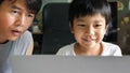Authentic asian child boy using laptop with father. Kid smile with happy face looking to notebook for studying at home. Education Royalty Free Stock Photo