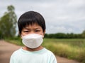 Authentic asian child boy wearing medical face mask to prevent from corona virus or covid-19 outdoor in nature background. Royalty Free Stock Photo