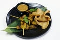 Authentic Asiatic street food chicken satay with peanut sauce and shrimps crackers on bamboo leaves Royalty Free Stock Photo