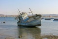 Authentic blue fishing boat at low tide at the bottom. Seascape with ships, yachts on horizon line background. Panorama of sunset. Royalty Free Stock Photo