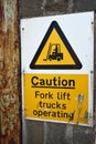 Authentic Caution Fork lift trucks operating sign with industrial wall background Royalty Free Stock Photo