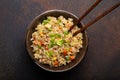 Authentic Chinese and Asian fried rice with egg and vegetables in ceramic brown bowl top view, dark rustic concrete Royalty Free Stock Photo