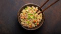 Authentic Chinese and Asian fried rice with egg and vegetables in ceramic brown bowl top view, dark rustic concrete Royalty Free Stock Photo