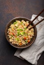 Authentic Chinese and Asian fried rice with egg and vegetables in ceramic brown bowl top view, dark rustic concrete Royalty Free Stock Photo