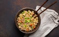 Authentic Chinese and Asian fried rice with egg and vegetables in ceramic brown bowl top view, dark rustic concrete Royalty Free Stock Photo