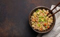 Authentic Chinese and Asian fried rice with egg and vegetables in ceramic brown bowl top view on dark rustic concrete Royalty Free Stock Photo