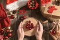 Authentic close-up Christmas photo. Woman`s hands hold log of tree with red balls in the form of Christmas tree next to other