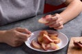 Authentic female hands holding a piece of a fresh cutting ripe peach on white plate