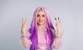 An authentic girl with pink hair in braids shows the victory sign with both hands. White background