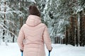 An authentic girl in a pink jacket is engaged in Nordic walking, skiing in a winter park