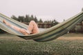 Authentic image of feet of child lying on hammock. Girl resting in countryside on background of wooden fence and grass Royalty Free Stock Photo