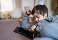 Authentic Kid sitting on sofa watching cartoons or playing games on tablet,Child boy using digital pad learning lesson on internet Royalty Free Stock Photo