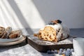 Authentic lifestyle Christstollen sliced on pieces, on wooden board, with natural sunlight shadows, traditional Christmas stollen