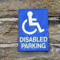 Authentic painted blue and white disabled parking sign on rustic stone wall Royalty Free Stock Photo