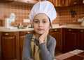 Adorable child girl in chef hat and apron, little baker confectioner looks at camera. Cooking class. Kids learn culinary