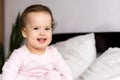 Authentic portrait caucasian little infant chubby baby girl or boy in pink sleepy upon waking looking at camera smiling