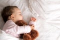 Authentic portrait cute caucasian little infant chubby baby girl or boy in pink sleep with teddy bear on white bed