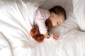 Authentic portrait cute caucasian little infant chubby baby girl or boy in pink sleep with teddy bear on white bed Royalty Free Stock Photo