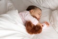 Authentic portrait cute caucasian little infant chubby baby girl or boy in pink sleep with teddy bear on white bed Royalty Free Stock Photo