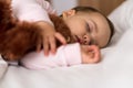 Authentic portrait cute caucasian little infant chubby baby girl or boy in pink sleep with teddy bear on white bed Royalty Free Stock Photo