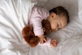 Authentic portrait cute caucasian little infant chubby baby girl or boy in pink sleep with teddy bear on white bed Royalty Free Stock Photo