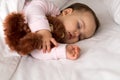 Authentic portrait cute caucasian little infant chubby baby girl or boy in pink sleep with teddy bear on white bed Royalty Free Stock Photo