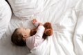 Authentic portrait cute caucasian little infant chubby baby girl or boy in pink sleep with teddy bear on white bed Royalty Free Stock Photo