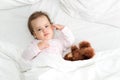 Authentic portrait cute caucasian little infant chubby baby girl or boy in pink sleepy upon waking with teddy bear Royalty Free Stock Photo