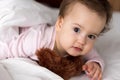 Authentic portrait cute caucasian little infant chubby baby girl or boy in pink sleepy upon waking with teddy bear Royalty Free Stock Photo