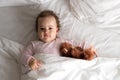 Authentic portrait cute caucasian little infant chubby baby girl or boy in pink sleepy upon waking with teddy bear Royalty Free Stock Photo