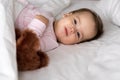 Authentic portrait cute caucasian little infant chubby baby girl or boy in pink sleepy upon waking with teddy bear Royalty Free Stock Photo