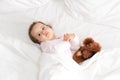 Authentic portrait cute caucasian little infant chubby baby girl or boy in pink sleepy upon waking with teddy bear Royalty Free Stock Photo