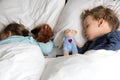 Authentic portrait cute caucasian little preschool siblings baby boy and girl in blue sleep with teddy bear on white bed