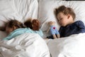 Authentic portrait cute caucasian little preschool siblings baby boy and girl in blue sleep with teddy bear on white bed