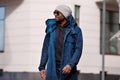 Authentic Portrait of handsome African American man walking in city, wearing stylish outfit parka coat, hoodie, knitted Royalty Free Stock Photo