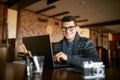 Authentic portrait of young smiling businessman looking at camera with laptop in office. Hipster man in glasses and Royalty Free Stock Photo