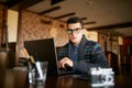 Authentic portrait of young confident businessman looking at camera with laptop in office. Hipster man in glasses and Royalty Free Stock Photo