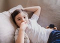 Authentic portrait Kid lying on safa biting his finger nails while watching TV, Little boy lying on couch bite his nails, Child Royalty Free Stock Photo