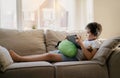 Authentic portrait Kid sitting on sofa watching cartoons on tablet,Yong boy playing game on touch pad, Child lying on couch