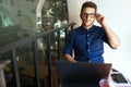 Authentic portrait of young confident businessman looking at camera with laptop in office. Hipster man in glasses doing