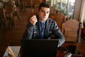 Authentic portrait of young confident businessman looking at camera with laptop tablet and smartphone on table. Hipster Royalty Free Stock Photo