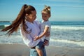 Authentic young woman, mother holding her little daughter in her arms, enjoying happy weekend together on the beach Royalty Free Stock Photo