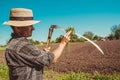 Authentic rural farmer in straw hat clean scythe with grass. Agriculture worker. Sharp blade. Vegetable garden. Farm implements.