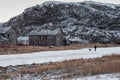 Authentic Russian northern village old dilapidated wooden houses harsh Arctic nature. A man walks with a dog. Teriberka. Russia